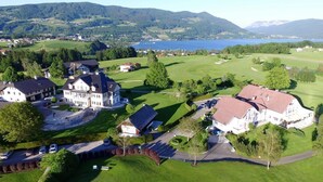 A large estate with multiple buildings, a golf course, and a lake in the background. - Hotel Drachenwand - Mondsee (Sankt Lorenz)