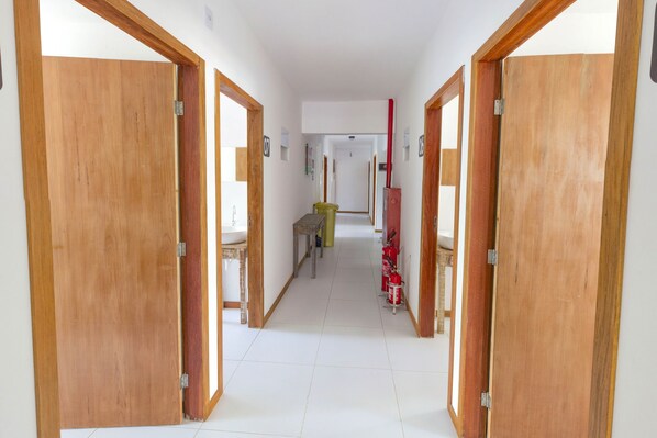 A hallway with wooden doors, a bench, and a fire extinguisher. - Economy Apart (Natal)