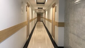 A long, narrow hotel corridor with doors on both sides, a polished floor, and recessed lighting on the ceiling.