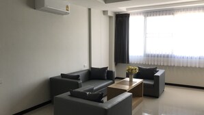 A modern living room with two grey sofas, a wooden coffee table, and a vase with flowers.