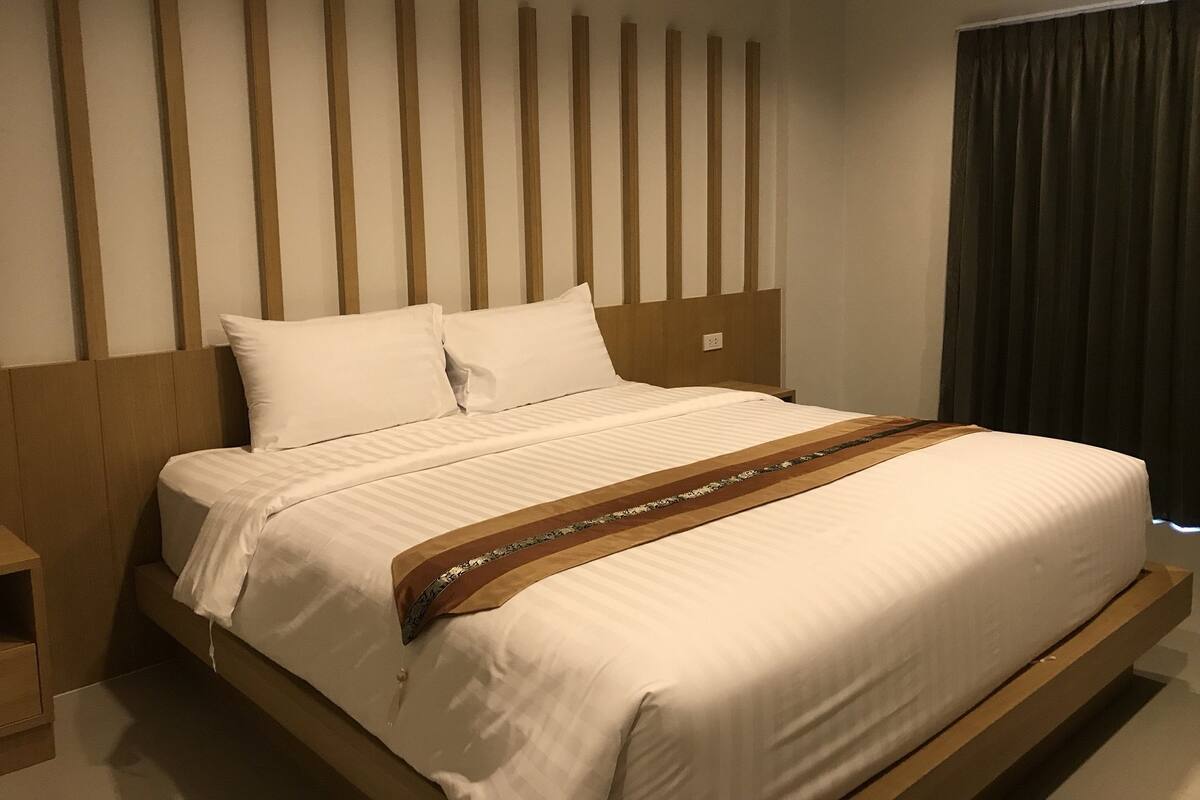 Een moderne hotelkamer met een groot bed, een houten hoofdeinde en uitzicht op de stad.