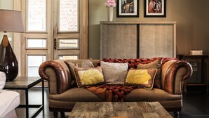 A living room with a brown leather sofa, a wooden coffee table, and a lamp. There is a brick wall and a door with glass panels. - Holiday Home Babillie (Roeselare)