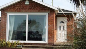 Une maison de plain-pied en briques, dotée d’une grande porte-fenêtre coulissante et d’un petit porche à l’avant.