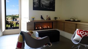 Una sala de estar con chimenea, un ventanal y vistas al exterior.