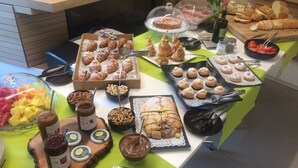Un bufé con diversos pasteles, mermeladas y frutas.