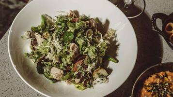 Een bord met gemengde salade, diverse groenten en mogelijk ook een beetje eiwit, geserveerd op een wit bord.
