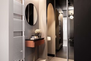 Un baño moderno con radiador blanco, espejo y tocador con artículos de aseo.