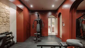 A gym with a bench, dumbbells, and weight machines.