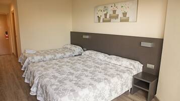 A hotel room with two beds, a wooden floor, a painting on the wall, and a small bedside table.