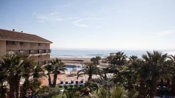 A resort with a pool, palm trees, and a view of the ocean.