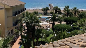 Un resort con piscina, palmeras y vista a la playa y al océano.