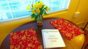 A table with a red floral tablecloth, a vase with yellow flowers, and a 'Guest Reference Guide' on it.