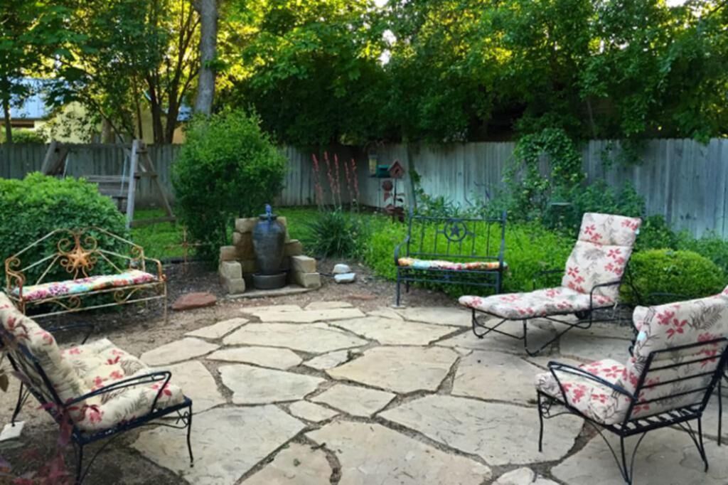 A patio with stone flooring and four floral-patterned chairs.