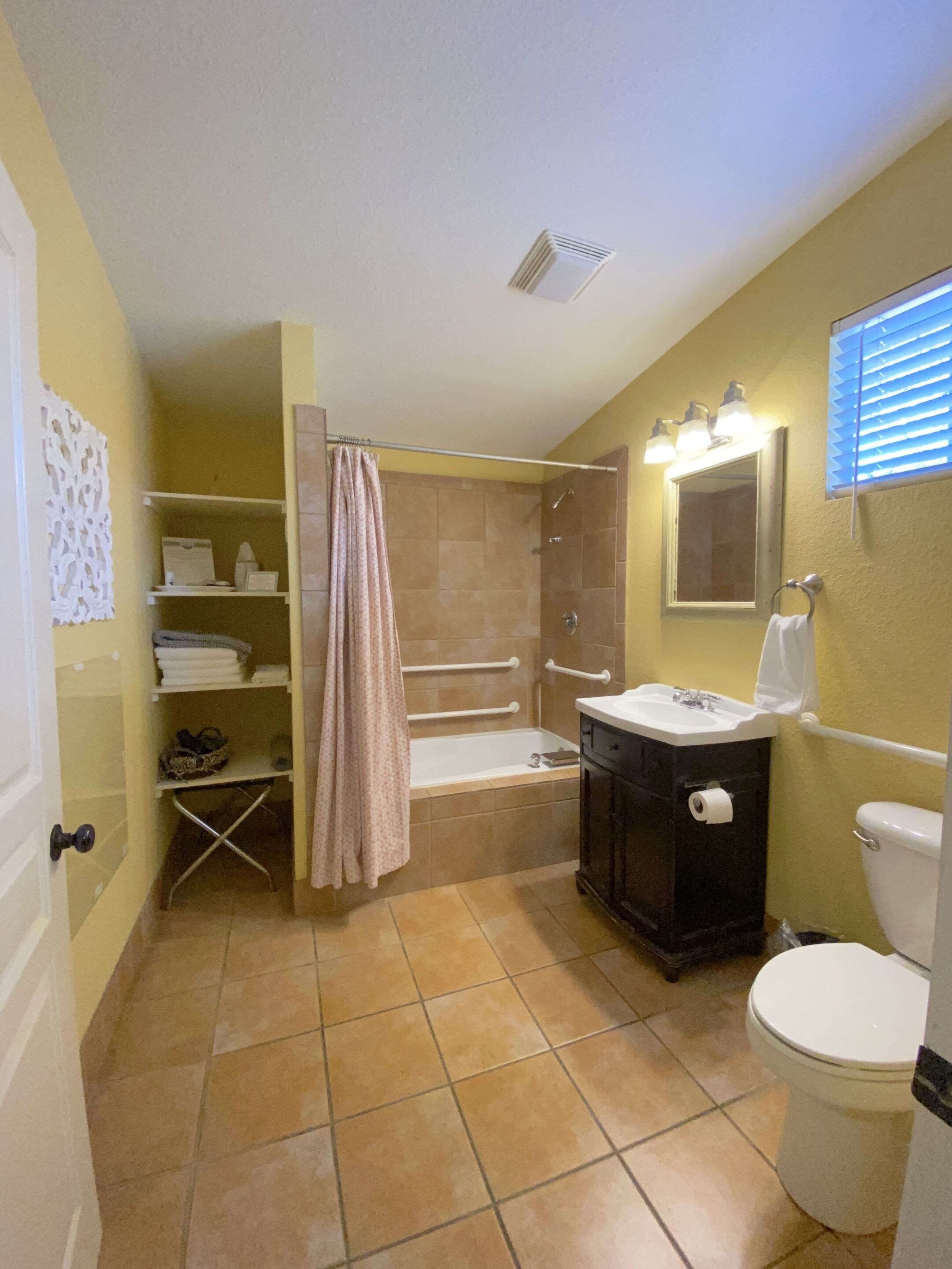 A compact bathroom with a shower, toilet, sink, and storage shelves.
