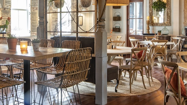 A dining area with wicker chairs, a central table, and hanging wicker chandeliers. - Inn at I'On, an Ascend Collection Hotel (Mount Pleasant)