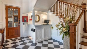 A reception area with a checkered floor, a wooden staircase, and a reception desk with a computer. - Inn at I'On, an Ascend Collection Hotel (Mount Pleasant)