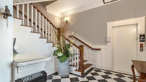 A staircase with a white railing, a potted plant, a black 'KEY DROP' box, and a checkered floor. - Inn at I'On, an Ascend Collection Hotel (Mount Pleasant)