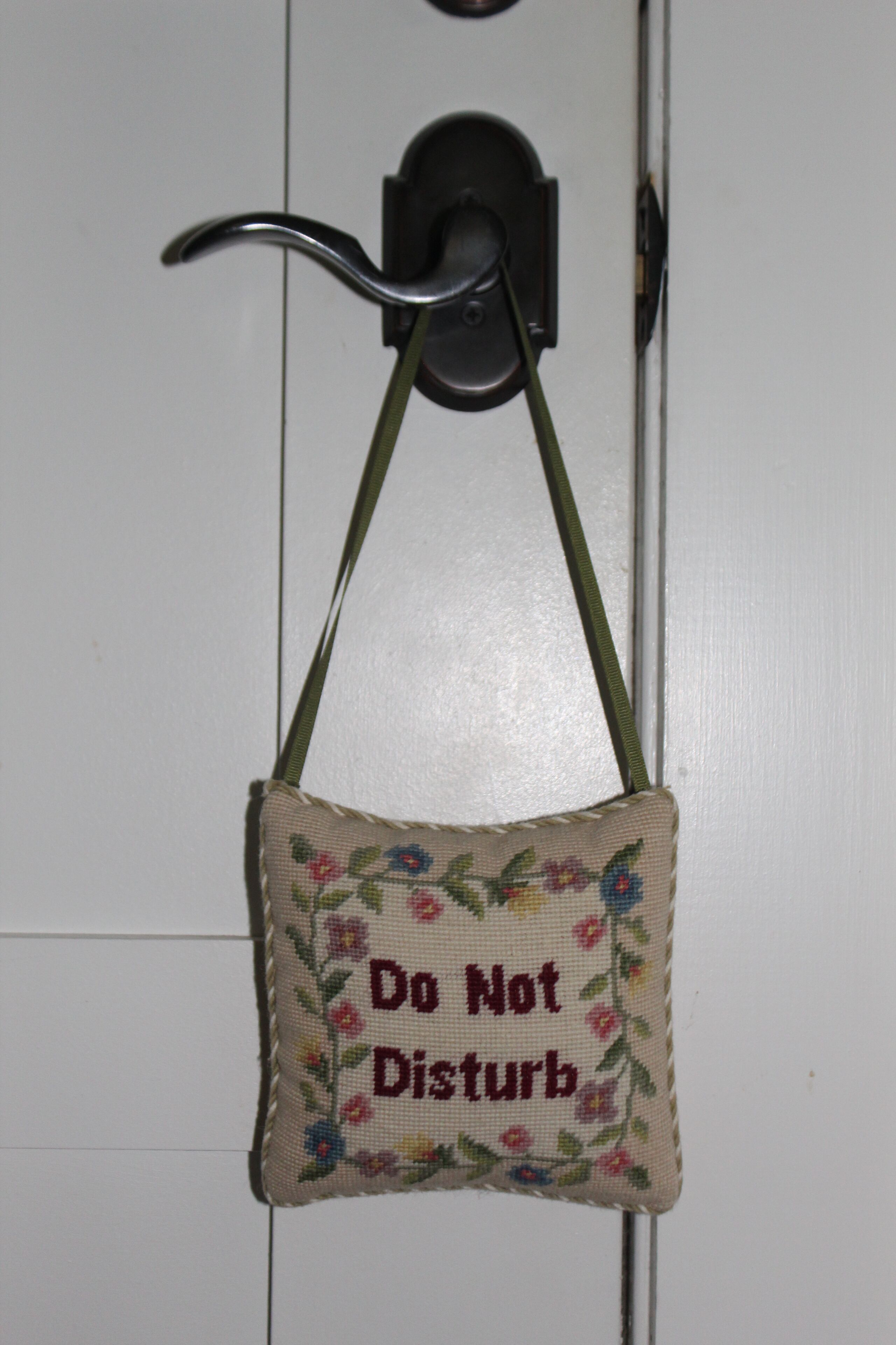 A small embroidered sign with the text "Do Not Disturb" hanging on a door.