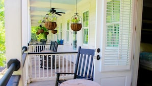 A porch with a table and chairs, hanging flower baskets, and a door with shutters. - Inn at I'On, an Ascend Collection Hotel (Mount Pleasant)