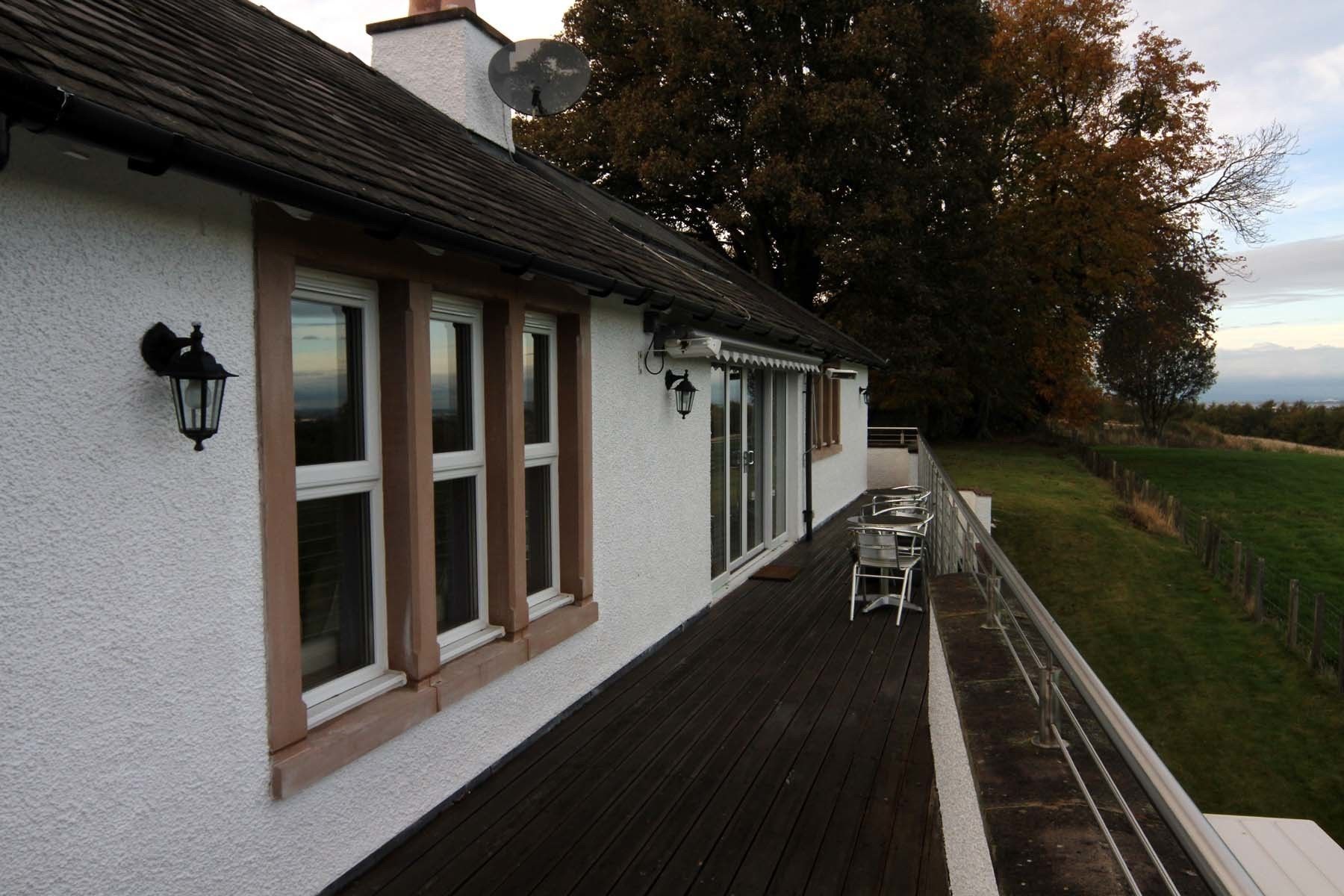 A white building with multiple windows and a wooden deck.