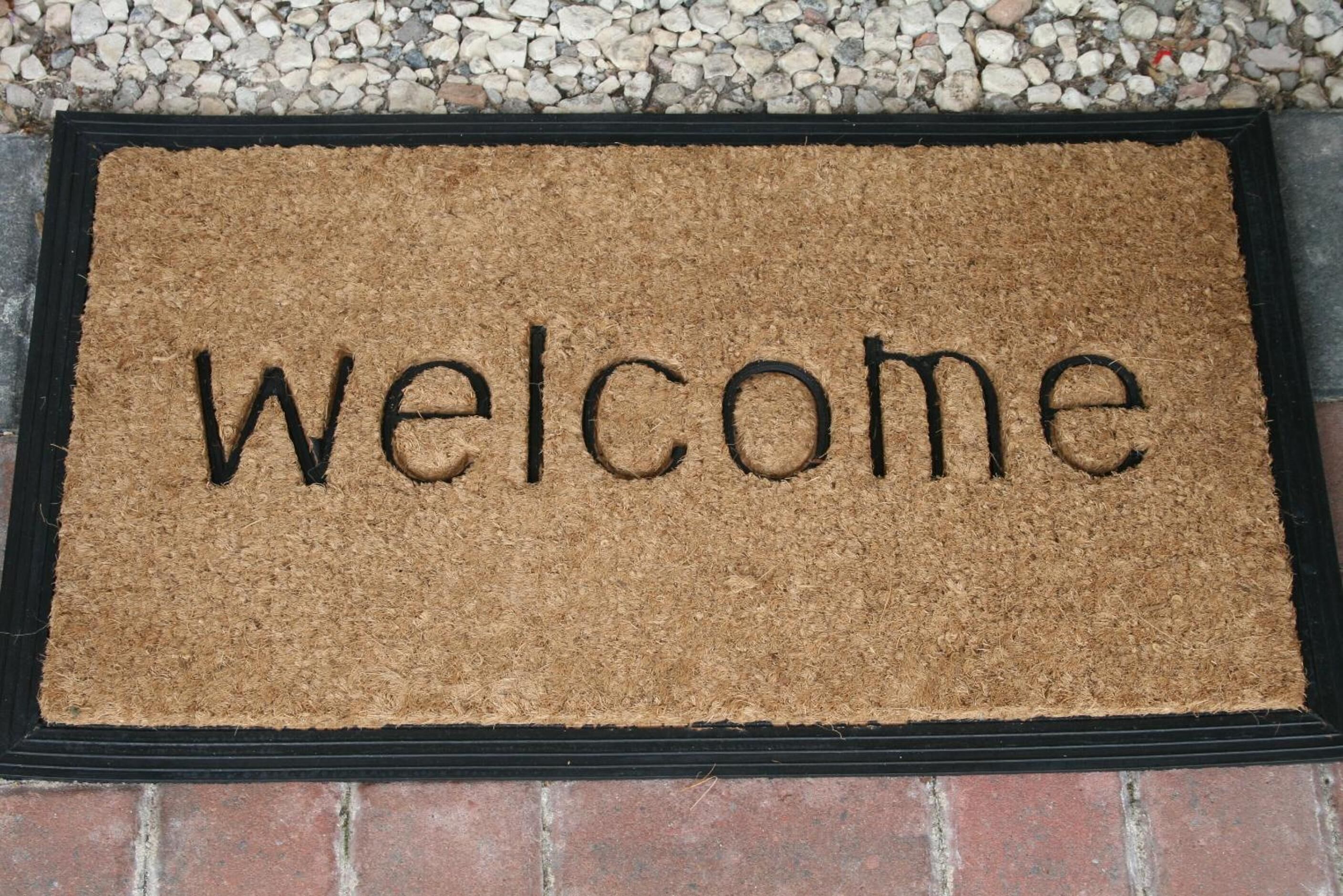 Eine Fußmatte mit dem Wort 'Welcome' in schwarzen Lettern.