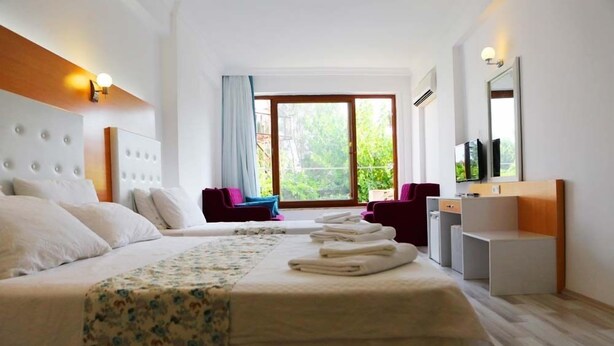 Une chambre d’hôtel avec un grand lit, un bureau, une chaise et une fenêtre donnant sur un paysage verdoyant.
