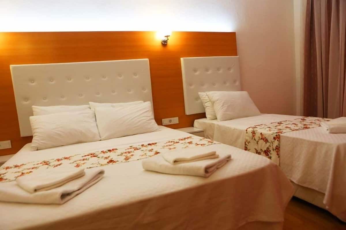 A hotel room with two beds, each with a white headboard and floral bedspread.