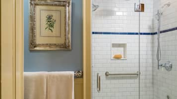 Une salle de bain avec un tableau encadré au mur, un porte-serviettes et une douche aux carreaux blancs avec une bande bleue.