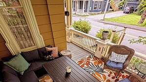 En veranda med sofa, stole, et bord og en dekorativ måtte.