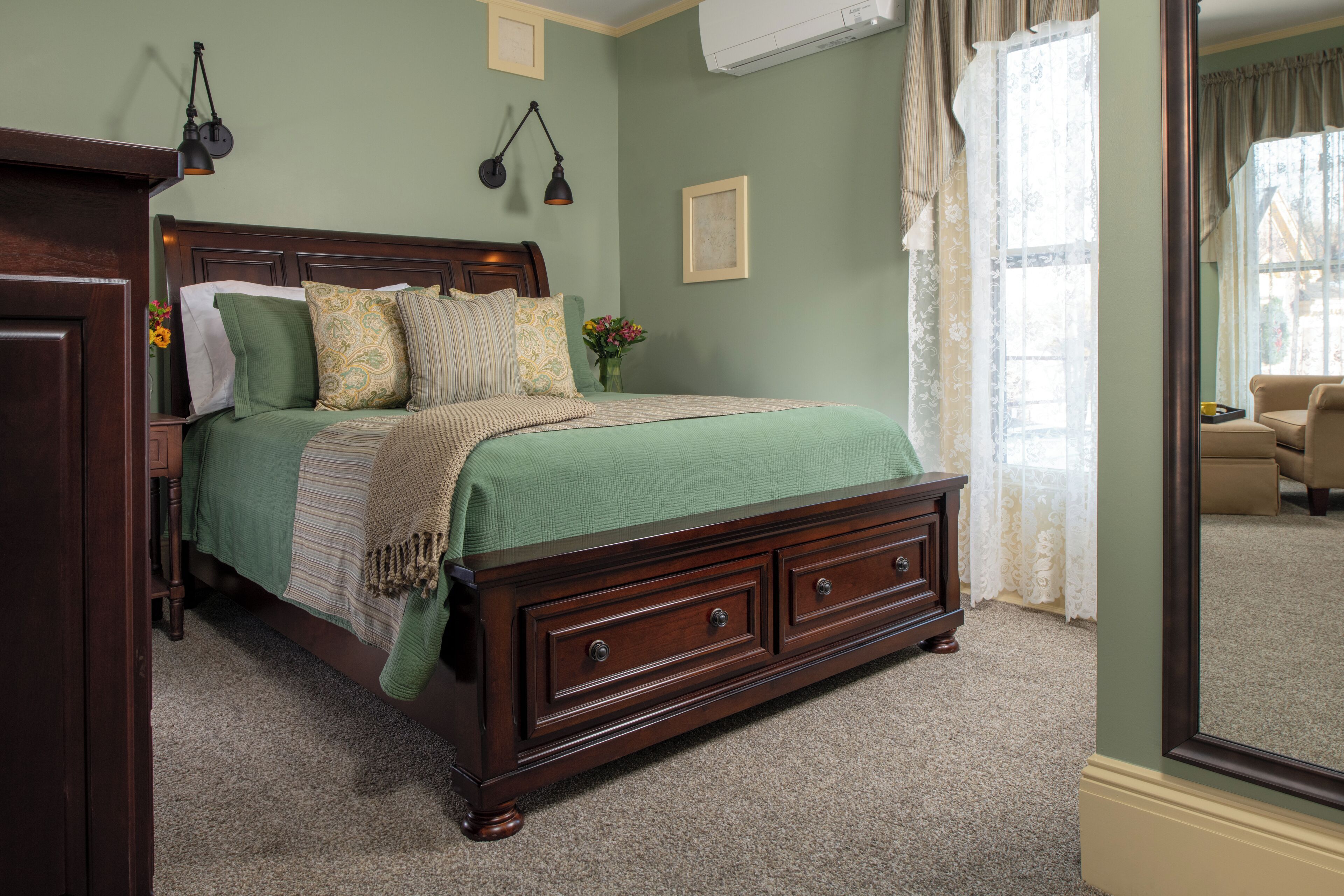 Un dormitorio con cama de madera, dos lámparas de noche, un tocador y un espejo grande.