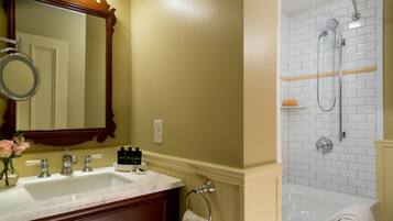 A bathroom with a double sink, a large mirror, and a shower area with a white tiled wall.