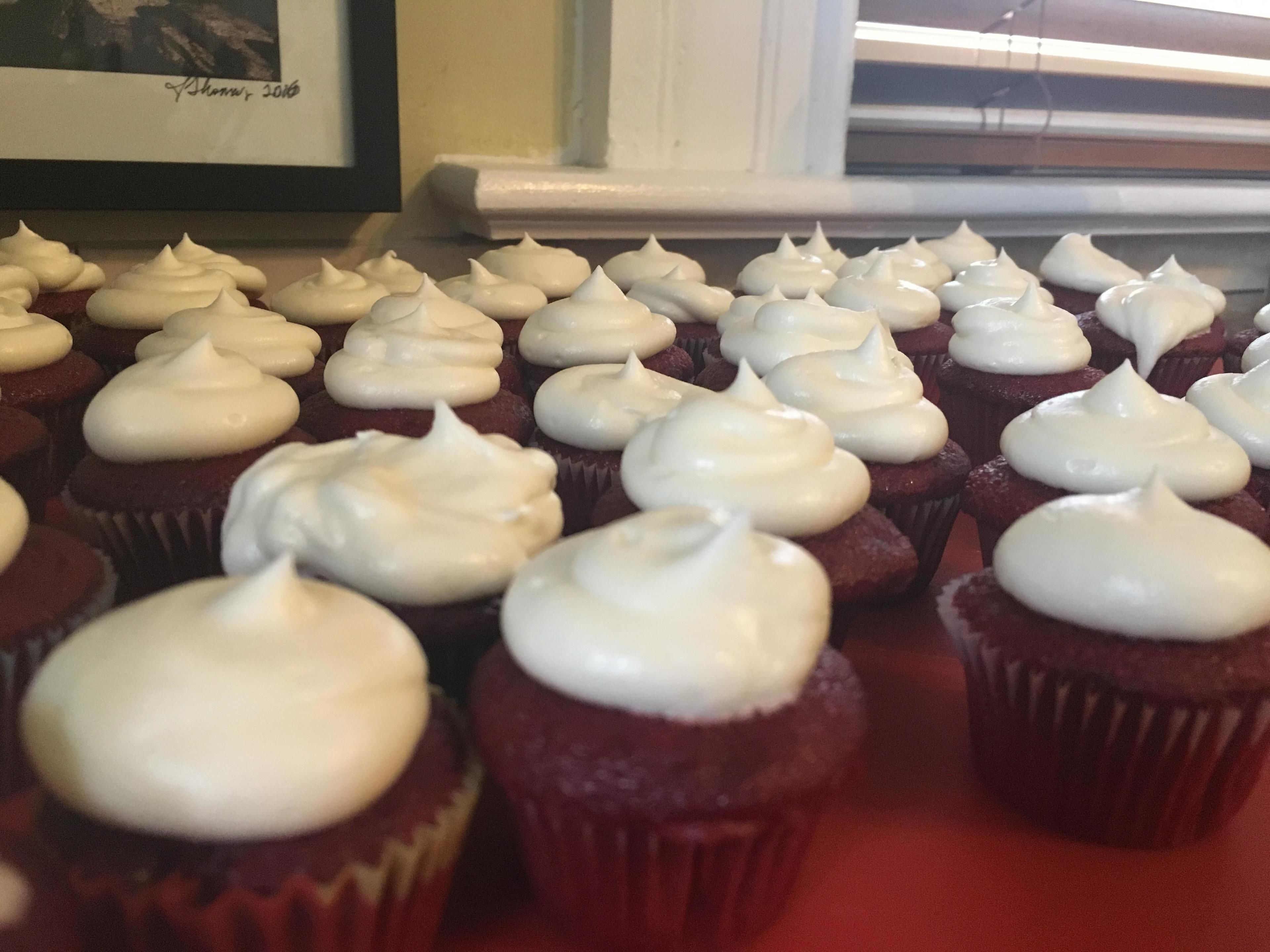 A collection of cupcakes with white frosting arranged on a table.