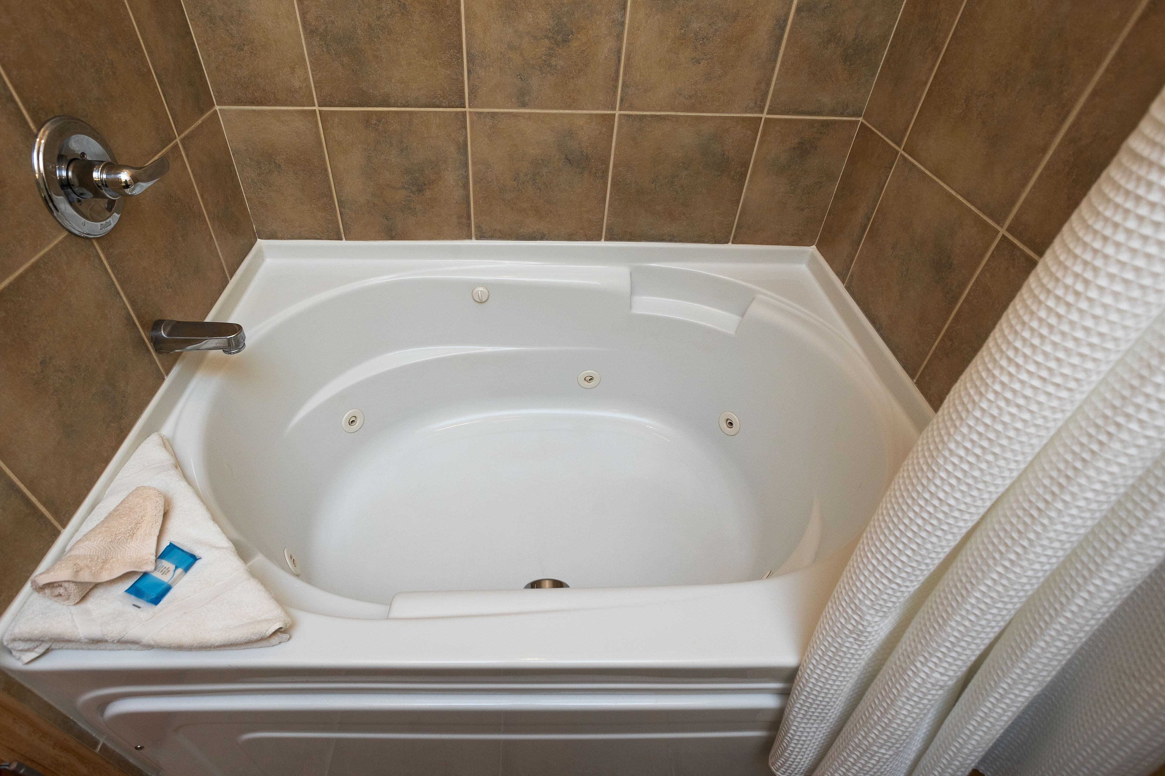 Un baño con bañera, una toalla y cortina de ducha.