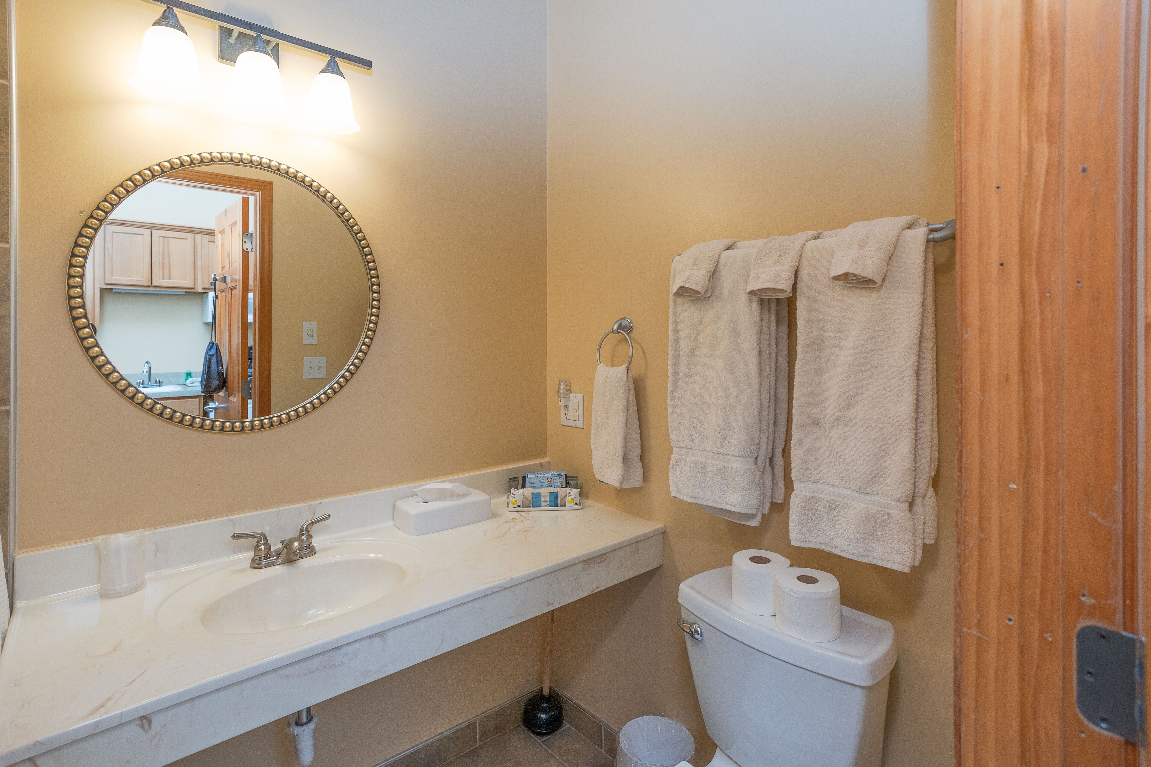 A bathroom with a sink, mirror, toilet, and towels.