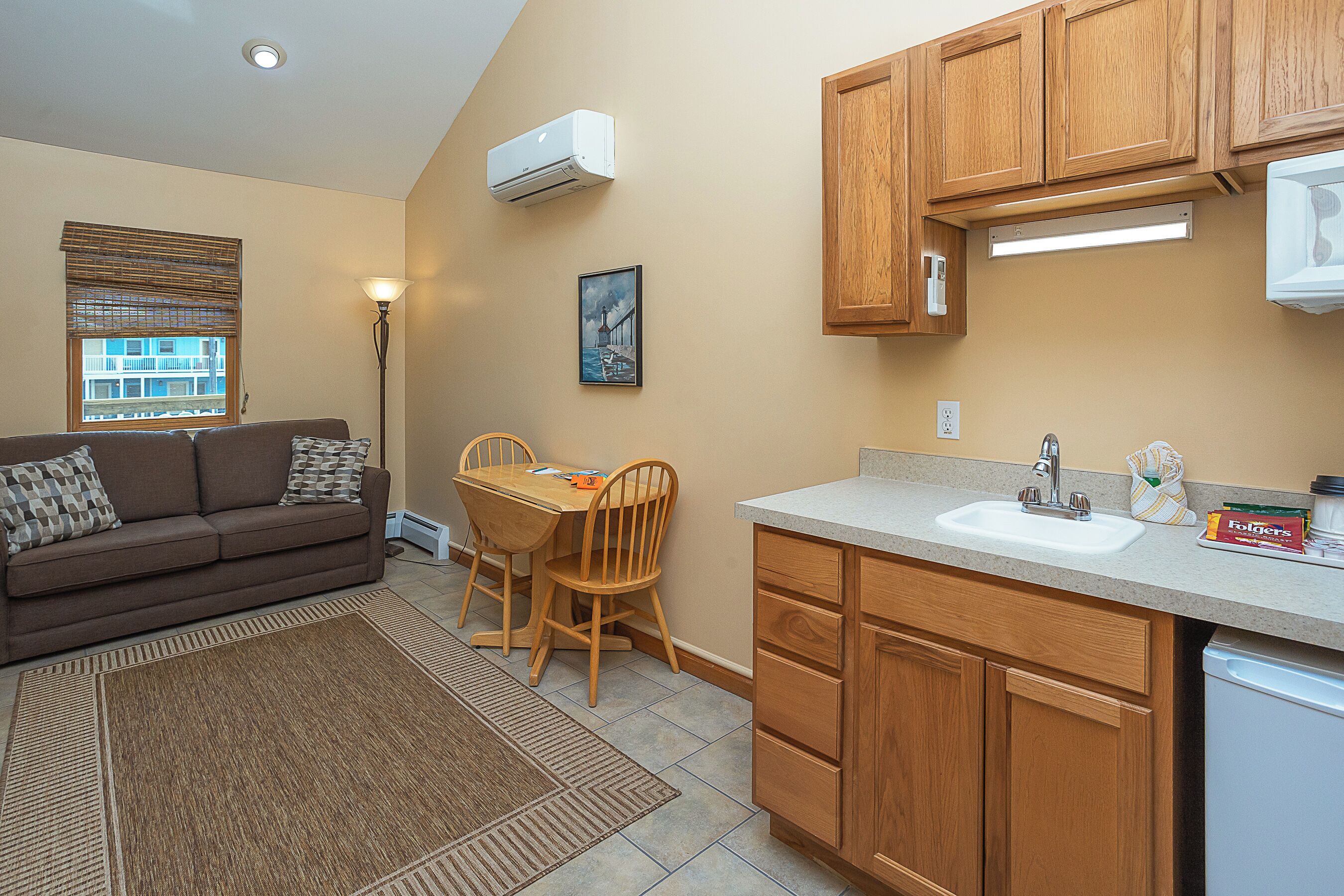 A compact kitchen with wooden cabinets, a built-in sink, and a dining area with a table and chairs.