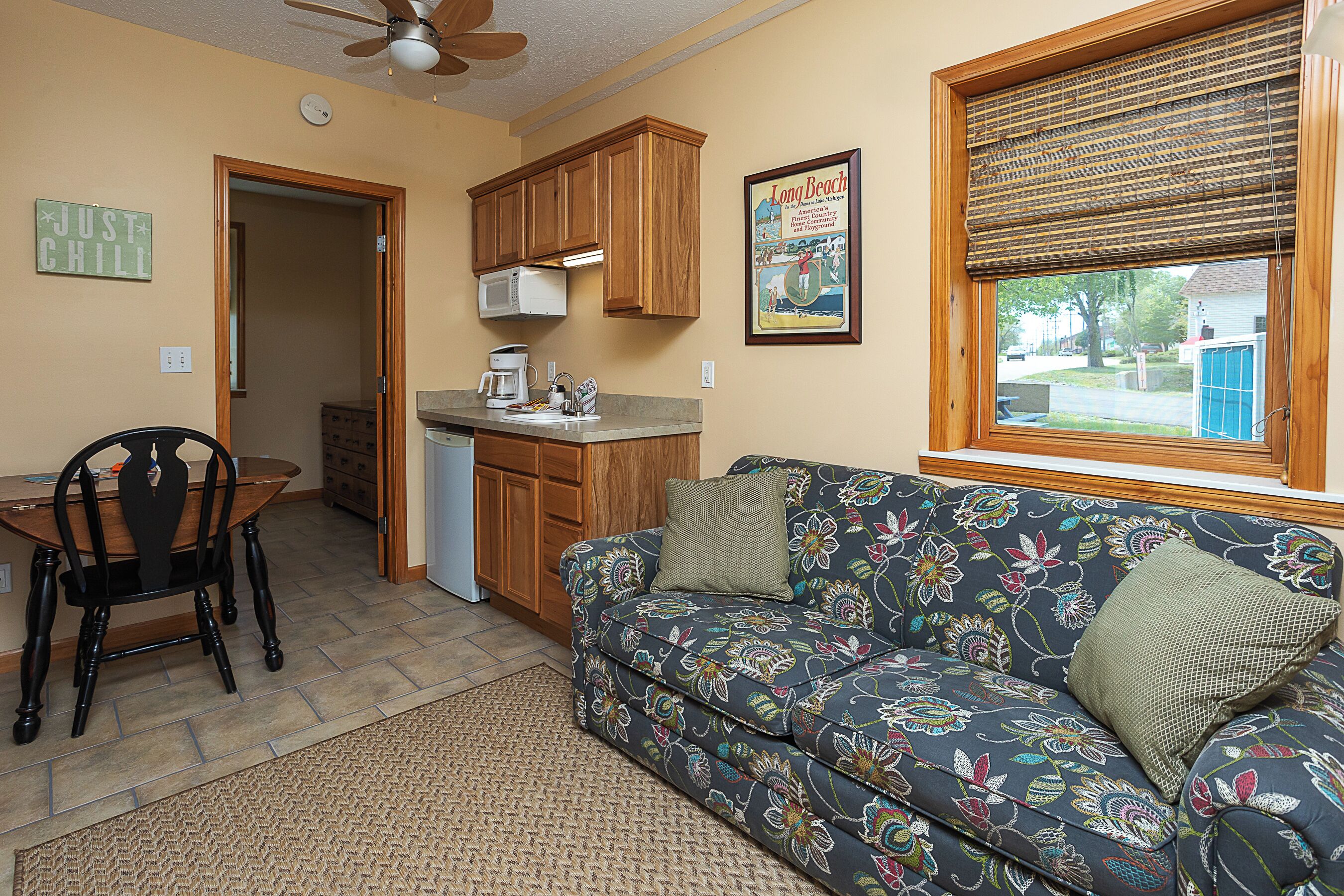A compact living space with a kitchenette, a dining area, and a sofa with floral upholstery.