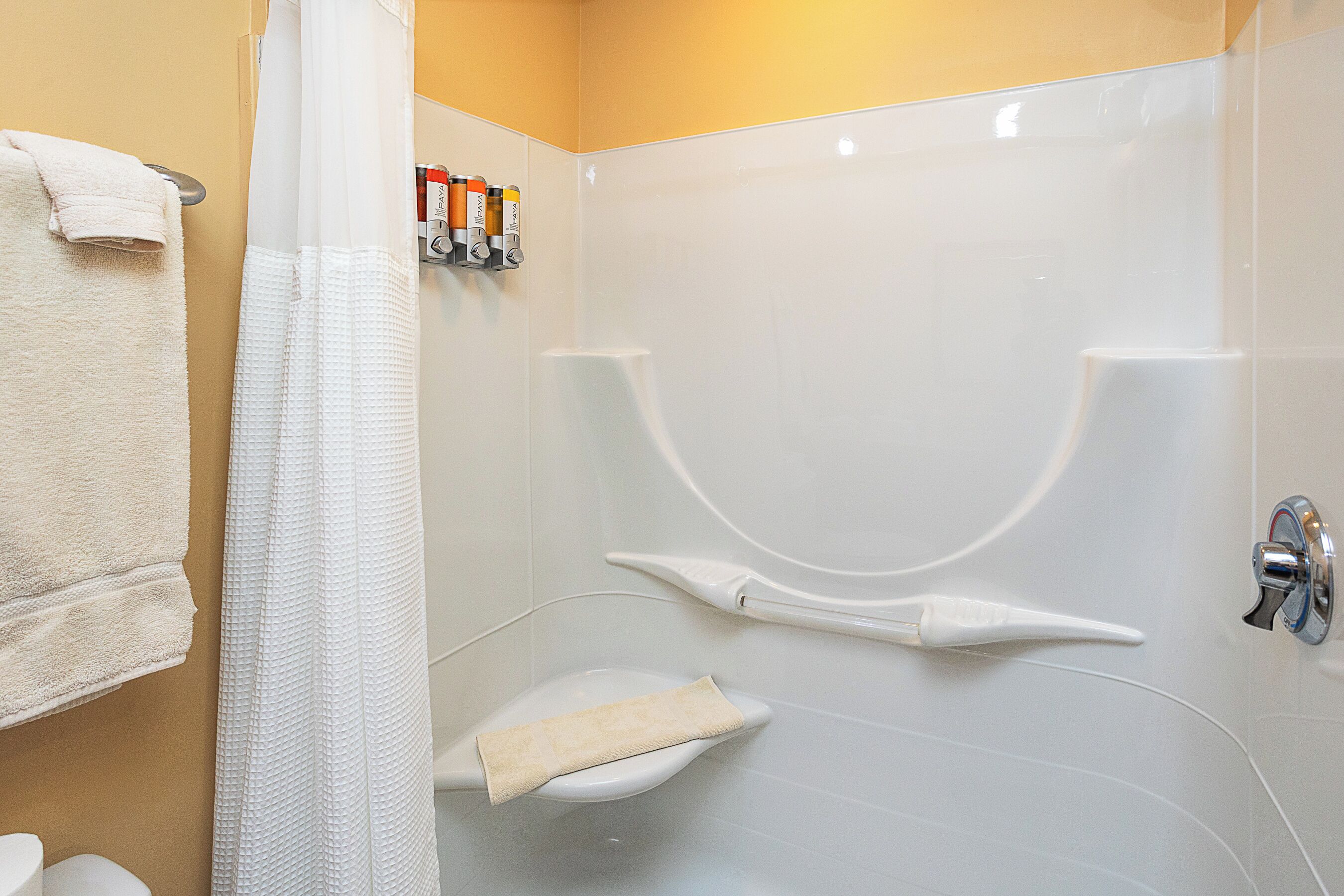 Un baño con ducha, inodoro y un perchero con toallas.