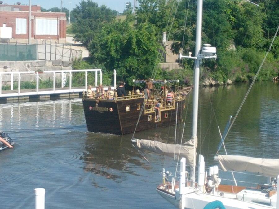 A wooden boat docked at a pier with passengers on board.