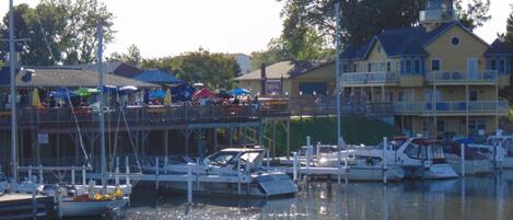 A marina with boats docked, a pier with people, and a building with balconies.