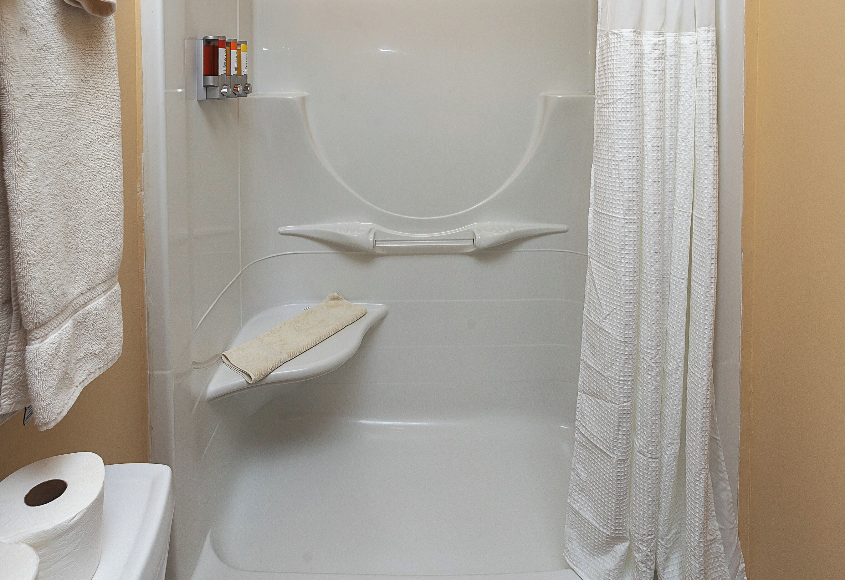 A bathroom with a toilet, a towel rack, and a shower curtain.