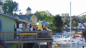 A waterfront building with a balcony overlooking a marina. - Bridge Inn (Michigan City)