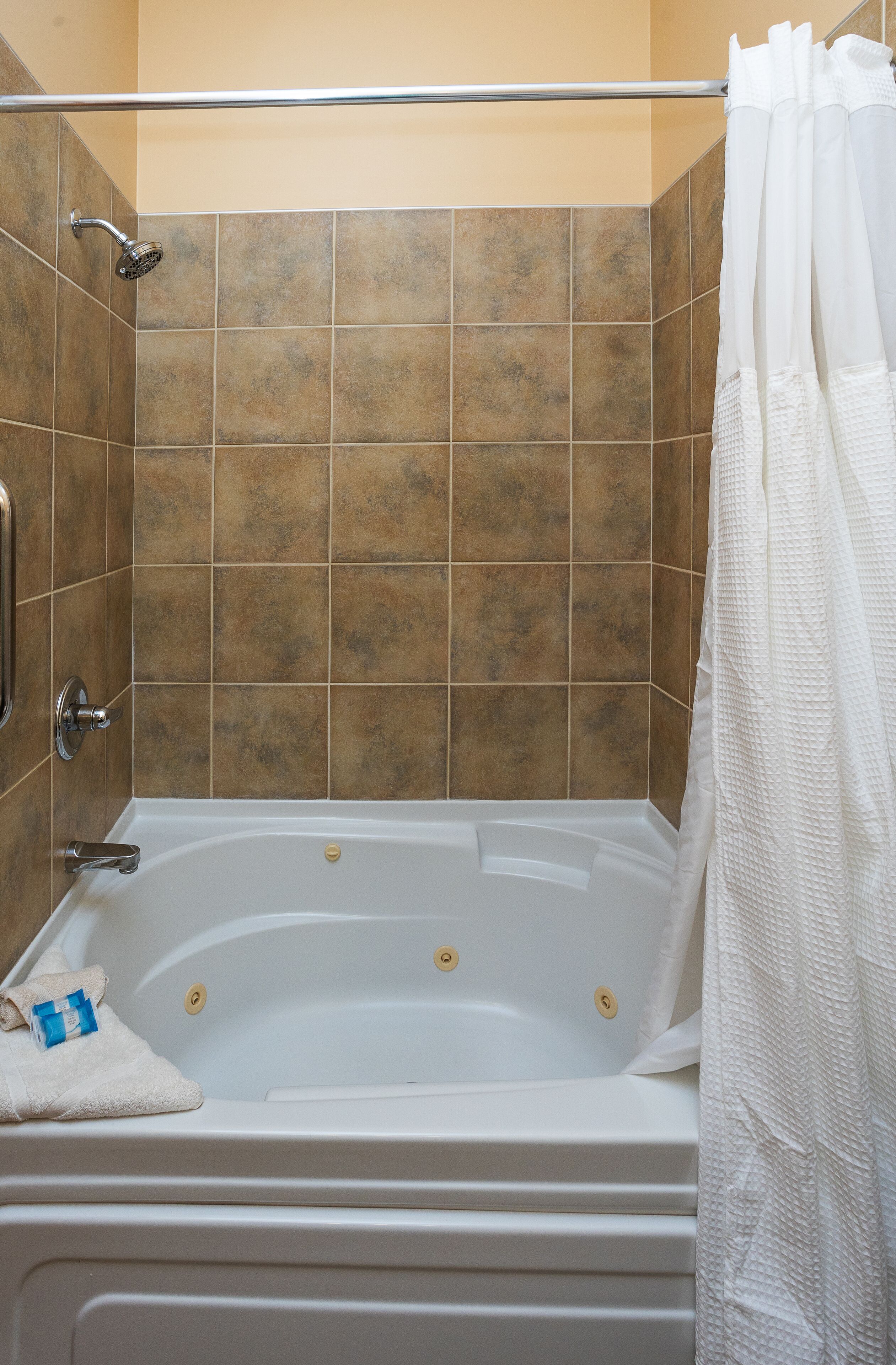 Un baño con bañera, ducha y paredes de azulejos.
