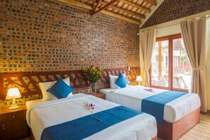Une chambre d’hôtel avec deux lits, un mur en briques, des poutres en bois au plafond et une fenêtre avec des rideaux.