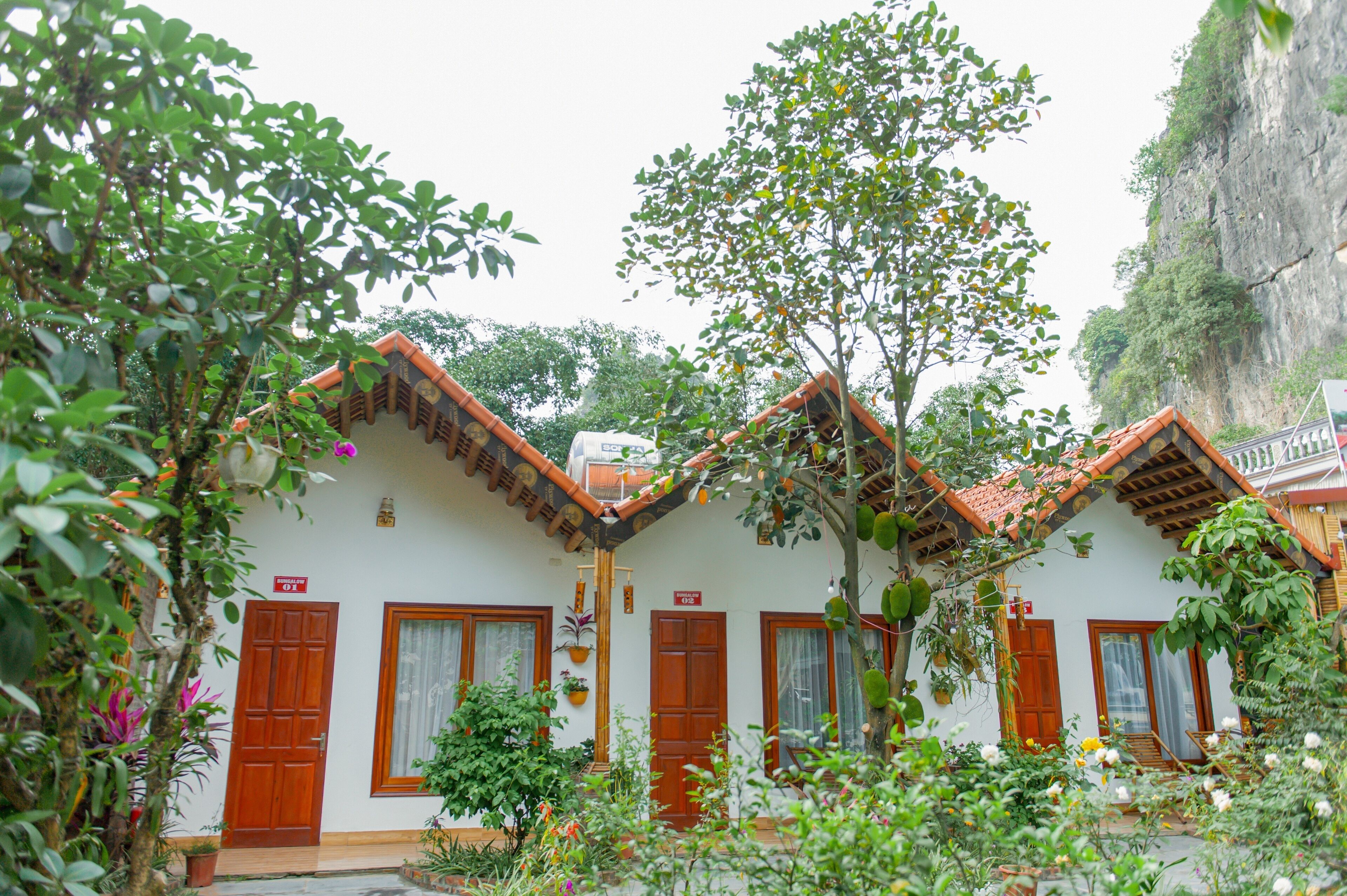 A traditional building with a tiled roof, wooden doors, and a garden with various plants.