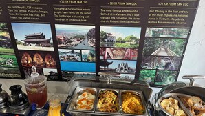 Un buffet proposant une variété de plats, avec un écran en arrière-plan affichant des informations sur les attractions locales.