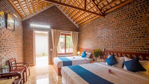 Une chambre d’hôtel avec deux lits, des meubles en bois, un mur en briques et un plafond en bois.
