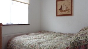 A bedroom with a bed, a window, and a framed picture on the wall. - Leysdown Chalet 28 (Sheerness)