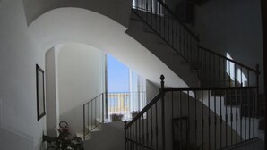 A spacious interior with a curved staircase, a potted plant, and a view of the outdoors. - Residenza D'Epoca 1861 (Castellabate)