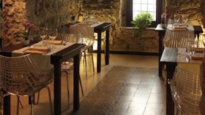 A stone-walled dining area with a high table and chairs, a window with a view, and a rustic interior. - Residenza D'Epoca 1861 (Castellabate)