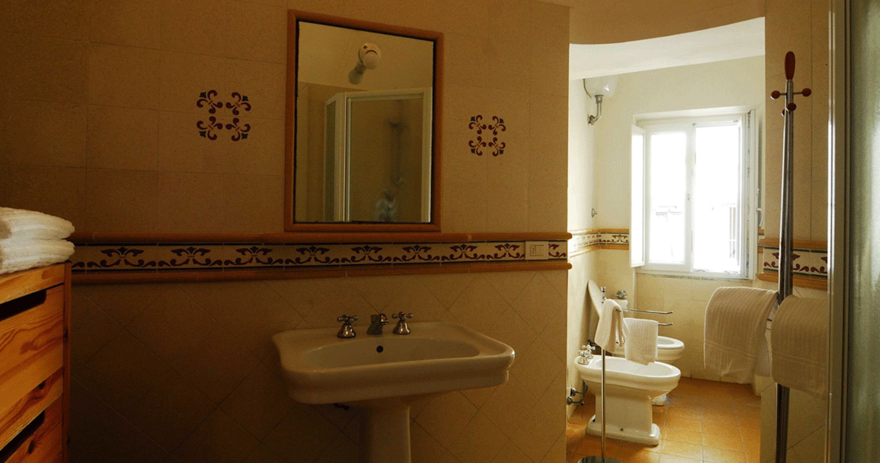 A bathroom with a sink, mirror, and two toilets.